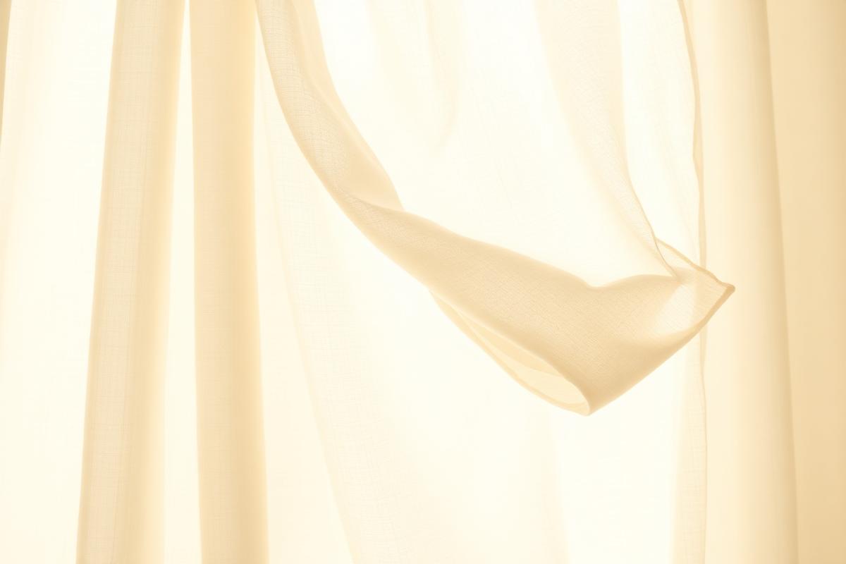 A linen curtain moving gently in warm sunlight